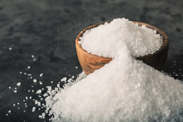 Salt. Coarse grained sea salt on granite - concrete  stone background with vintage spoon and wooden bowl — Stok fotoğraf