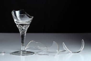 Kırık kristal şarap kadehi ve siyah arka planda cam kırığı..