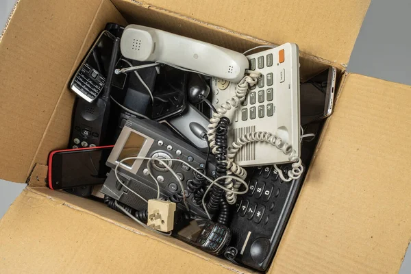 Eski masa telefonları, kablosuz telefon, cep telefonları, ve karton bir kutuda akıllı telefonlar.. 