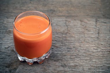 Ahşap dokusunun arka planında taze sıkılmış havuç suyu..