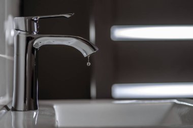 Banyodaki musluktan temiz su damlıyor. Seçici odak.