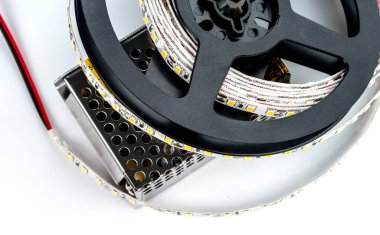 Beyaz zemin üzerinde 12 voltluk elektrik akımı sağlayan LED şeritli makaralar..
