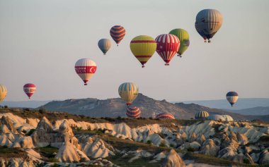 Goreme, Kapadokya, Türkiye 25 Nisan 2018 'de güneş doğarken Goreme yakınlarında birçok sıcak hava balonu havada uçuşuyor.. 