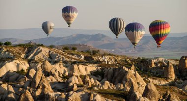 Goreme, Kapadokya, Türkiye 25 Nisan 2018 'de güneş doğarken Goreme yakınlarında birçok sıcak hava balonu havada uçuşuyor.. 