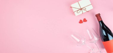 Sevgililer Günü tebrik kartı şablonu. Pembe arka plan, küçük kırmızı kalpler, gözlüklü bir şişe şarap ve hediye paketi. Uzayı kopyala Düz yatıyordu, üst Wiew