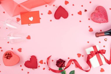 Sevgililer Günü tebrik kartı şablonu. Kırmızı kalpli pembe arka plan, bir şişe şarap, gözlük, kırmızı gül, hediye paketi ve kırmızı kurdele. Uzayı kopyala Düz yatıyordu, üst Wiew.