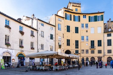 Lucca, İtalya-16 Şubat 2025: Güneşli bir günde Lucca 'nın ünlü Amfitiyatro Meydanı' nda barlar