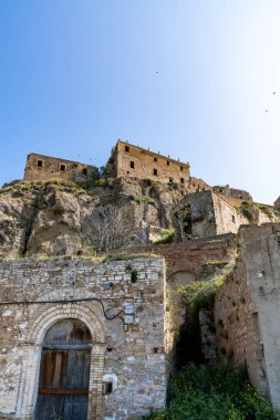 Craco, İtalya-25 Nisan 2025: Güneşli bir günde İtalya 'nın hayalet şehri Craco' nun kalıntılarının dikey fotoğrafı