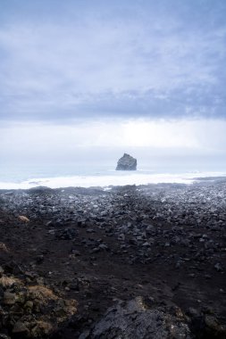 Bulutlu bir günde Reykjanes Yarımadası 'ndaki Valahnukamol denilen kıyıdaki kaya oluşumlarının dikey fotoğrafı