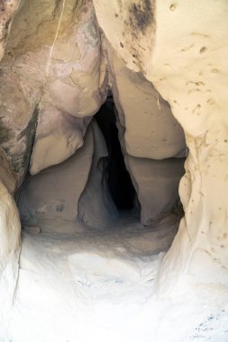 Bulutlu bir günde Emilia 'daki Soprasasso mağaralarında rüzgar ve suyla oyulmuş girişi gösteren dikey fotoğraf.