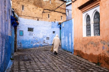 Chefchaouen, Fas - 26 Mart 2024: Bulutlu bir günde, Fas 'ın mavi şehri Chefchaouen' in dar sokaklarında tanınmayan bir kişi yürüyor..