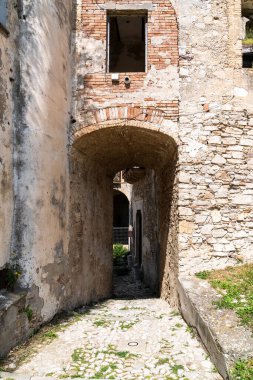 Craco, İtalya-25 Nisan 2025: Güneşli bir günde Craco harabelerinin arasından geçen küçük bir yolun dikey fotoğrafı