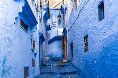 Chefchaouen, Fas - 26 Mart 2024: Bir bahar günü Fas 'ın Chefchaouen şehrinde tamamen mavi boyalı bir sokakta fener asılı.