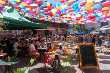 Catania, İtalya-14 Mayıs 2022: İnsanlar bir bahar günü Catania 'da pek çok renkli şemsiyenin gölgesinde barlarda oturuyorlar