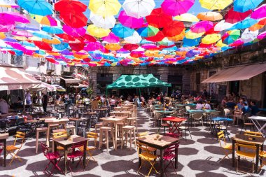 Catania, İtalya-14 Mayıs 2022: Bir bahar günü birçok renkli şemsiyenin gölgesi altında Catania 'da bir sürü insan barlarda oturuyor.
