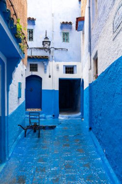 Chefchaouen, Fas - 26 Mart 2024: Mavi kapıların dikey fotoğrafı ve Fas 'ta mavi bir şehir olan Chefchaouen' da bir sokakta bir el arabası
