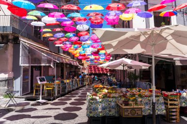 Catania, İtalya-14 Mayıs 2022: Birçok renkli şemsiye Mayıs ayının bir gününde Catania sokaklarını ve barlarını gölgeliyor