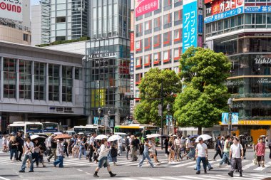 Tokyo, Japonya-Ağustos 7, 2024: Birçok insan, kendilerini güneşten korumak için şemsiyeli bir kalabalık, ağustosta bir gün Tokyo 'da Shibuya Geçidi' ni geçtiler..
