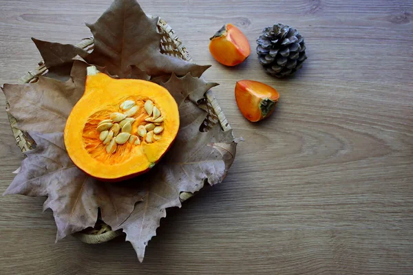 北海道産のカボチャは 秋の葉の上にウィッカーバスケットに入っています カボチャと柿の秋の静物 — ストック写真