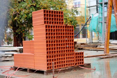 İnşaat alanında bir yığın kırmızı tuğla. İnşaat ve onarım için malzeme. Kil tuğla, tuğla dokusu, inşaat işlemine hazırlık.