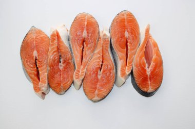 Beyaz arka planda altı büyük ve yağlı somon bifteği..  