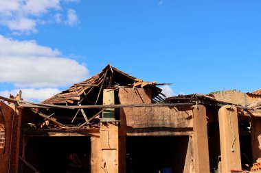 Mavi gökyüzüne karşı kiremitli çatısı tahrip olmuş tuğla üstüne tuğla bina..