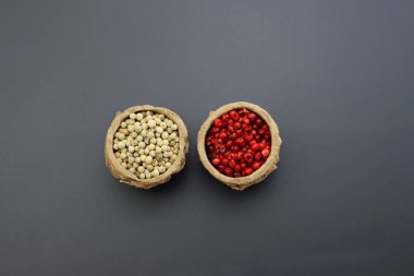 Gri arka planda yuvarlak kaselerde beyaz ve pembe biberler. Biber taneleri. 