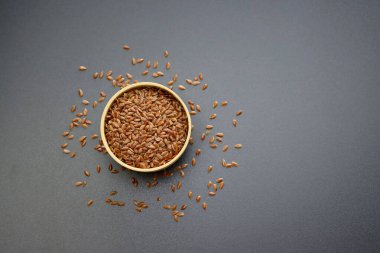 Kahverengi keten tohumu gri arka planda yuvarlak bir kasede.