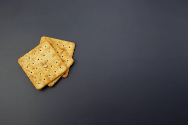 Gri arka planda kare krakerler. Ağız sulandıran buğday unlu kraker.