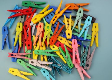 Mavi arka planda çok renkli plastik mandallar yığını. Parlak mandallar arkaplanı 