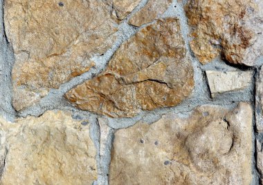 Bej taştan bir duvarın dokusu. Eski duvarın düz olmayan yüzeyi.