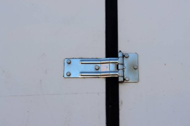 Çelik kapı menteşesi beyaz ahşap kapıya vidalanmış..