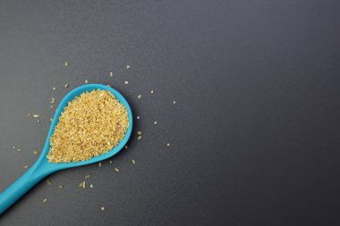 Gri arka planda mavi kaşıkta kuru bulgur taneleri. bulgur, Orta Doğu yemeklerinin temel öğesidir.