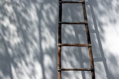 Gri ve beyaz bir duvarın arka planında tahta merdiven var. Merdivenlerin bir kısmı.