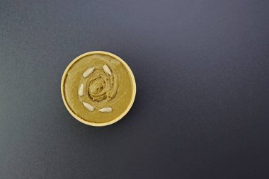 Gri arka planda yuvarlak bir kasede ayçiçeği tohumu ezmesi.