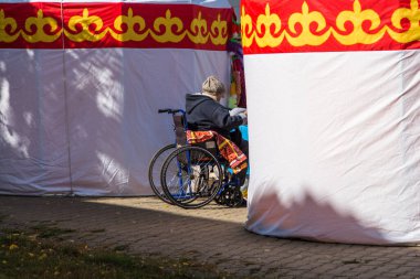 Uralsk, Kazakistan (Kazakistan), 23.09.2020: Tekerlekli sandalyede oturan engelli bir kadın en sevdiği aracıyla Kazak yurtları yakınlarında tekerlekli sandalyede oturuyor.