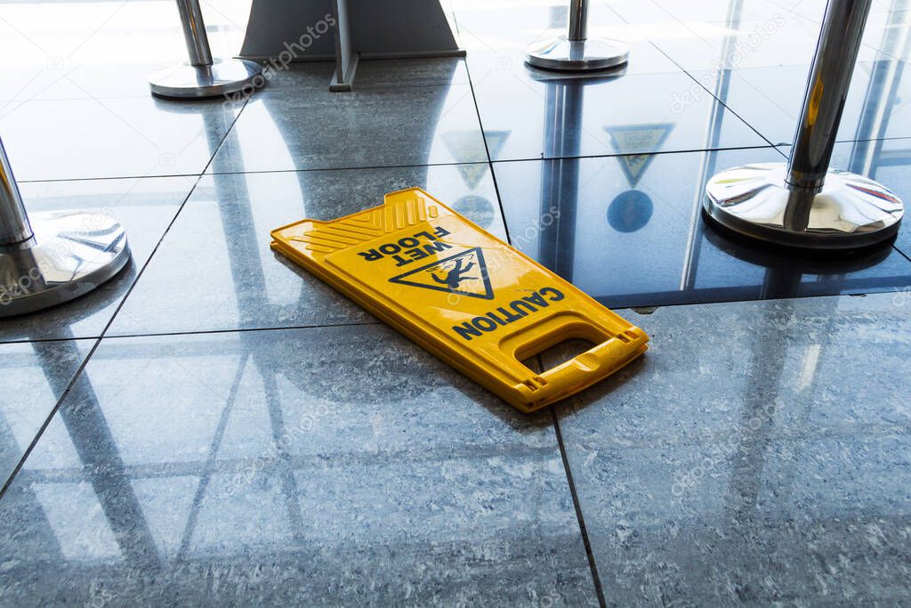 sign carefully wet floor lies on the airport floor, bright yellow sign caution wet floor