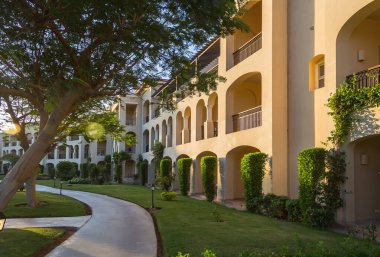 Jaz Mirabel otel binası ve Sharm el-Sheikh 'teki manikürlü yerler: gün batımında kemer, balkon ve yemyeşil verimli tropikal alanlar. Mısır 'daki otel alanı.