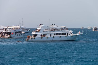Mısır, 4.10.2025 - Güneşli bir günde turistlerle birlikte beyaz yat gezisi. İnsanlar güvertede yüzüyor ve rahatlıyor. Mısır 'da dalış. Deniz kıyısında tatiller ve geziler.