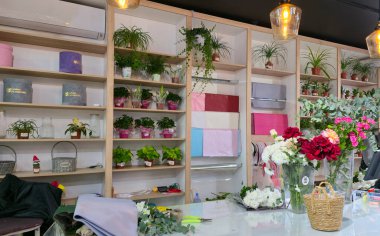 Uralsk, Kazakistan (Kazakistan), 15.11.2025 - Çiçekçi dükkanı veya çiçekçi stüdyosu iç mimarisi. Ev bitkileri ve hediye kutularıyla dolu raflar. Çiçek buketleri ve tezgahta ambalaj malzemeleri..