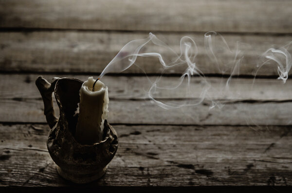 Fuming extinguished the candle on the wooden table