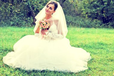 bir buket çiçek ile yeşil çayır mutlu gelin oturur