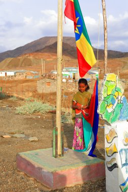 Schoolgirl raising the national and regional flags. Berahile-Ethiopia. 0374 clipart