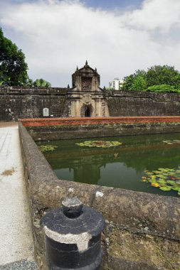 Fort Santiago 'nun 12 metre yüksekliğindeki ana kapısı kale duvarının güney cephesinden delindi ve hendeğin karşısında şehirden ayrılırken görüldü. Intramuros Duvarlı İç Şehir-Manila-Filipinler