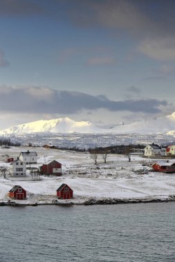 Holdoya Adası 'ndaki evler, Austvagoya Adası' ndaki Ringen köyünden Hadselfjorden 'in karşısındaki N.Coast' ta görüldü. Hadseloya adasının arka planındaki dağlar. Lofoten Vesteralen Adaları-Nordland Fylke-Norveç.