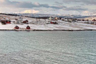 Holdoya Adası 'ndaki evler, Austvagoya Adası' ndaki Ringen köyünden Hadselfjorden 'in karşısındaki N.Coast' ta görüldü. Hadseloya adasının arka planındaki dağlar. Lofoten Vesteralen Adaları-Nordland Fylke-Norveç.