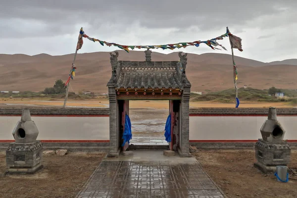 在沙漠中 一场小雨过后 东面挂着佛教祈祷旗 正面对着巴丹贾兰沙漠寺石制的入口拱门 Sumu Jaran Lake Inner Mongolia China — 图库照片