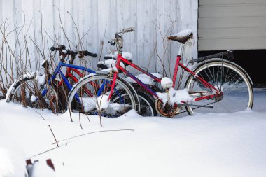 Eski, paslı, terk edilmiş bisikletler kalın kar örtüsünün altında yazın gelip kullanılmasını bekleyen bir balıkçı kulübesinin duvarına yaslanıyorlar. Hovsundhamm Limanı Gimsoya-Lofoten-Nordland-Norveç