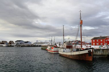 Eski ve modern balıkçı tekneleri. Metal ve ahşap gövdeleri limana demirli. Arka planda Vestvagoya 'nın balık tepelerini kurutmak için ahşap raflar ya da jöle. Laukvik-Vagan kommune-Austvagoya-Lofoten-Norveç.