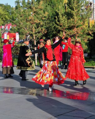 Zhangye, Çin-20 Ekim 2017: Uygurca giyinmiş yaşlı dansçılar şehrin Merkez Meydanı 'ndaki etnik müziğin sesine geleneksel koreografiler sergiliyorlar.